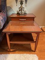 Pair of Mid-Century Modern style tiered end tables with glass tops, wood frame, tapered legs, and lower shelf.