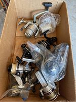 Box of 7 various open faced fishing reels, some plastic wrapped, showing condition and quantity