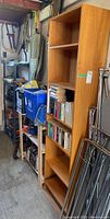 Three shelves lined up in a garage area showing solid wood bookshelf, wood shelf, and metal wire shelf. Contents on shelves consist of books and various items but are not included.