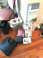 Shoe rack box standing vertically near other items; mix of boxed medical devices and a black soft bag on wooden floor