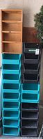 Photo showing two wooden shelves stacked on top of vertical columns of plastic sorting bins in blue and black colors.