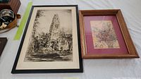 Framed 20th-century black and white cathedral tower engraving next to signed floral drawing with wooden frame and maroon matting