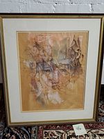 Framed pastel drawing of an abstract human face, beige background with pink, brown, and white highlights.