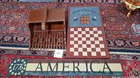 Lot showing cranberry scoop, Americana sign, and tile checkerboard hung on carpet.
