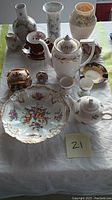 Photo showing a variety of porcelain items arranged on a table including bowls, vases, teapots, cups, and decorative boxes