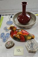 Overview of lot showing pottery bowl, red vase, duck figurine, windchime ceramic pieces, and two trinket boxes.
