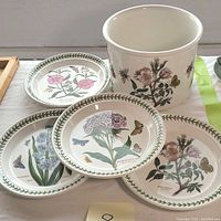 Photo of four round plates and one cache pot with botanical illustrations by Portmeirion Botanic Gardenware