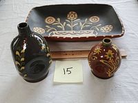 Three items shown together for size reference: two pottery bottles and a rectangular floral terra cotta dish with ruler