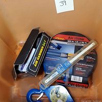 Photo of pneumatic air hammer set box, Legacy air hose in packaging, Blue Hawk metal pulley, and saw blades in plastic packaging in a bin