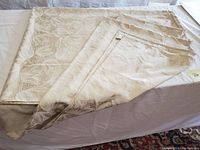 Full view of the Waterford floral damask tablecloth spread out and partially folded, showing the woven floral pattern and fabric texture.