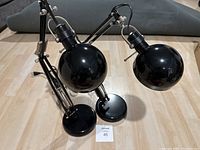 Two black articulated desk lamps seen from top angle showing lamp heads and arm joints.