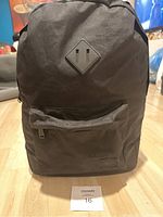 Full front view of the black Herschel backpack showing the front zip pocket and brand patch.