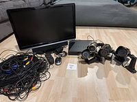 Overview of all components including 4 outdoor cameras, DVR unit, monitor, mouse, remote control and wiring cables arranged on the floor.