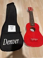 Cherry red Denver ukulele accompanied by a black soft case with 'Denver' branding.