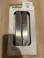 Two metal IKEA Bjarnum shelf brackets in original worn packaging, showing dimensions and quantity on box
