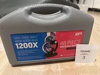 Carrying case with label showing that the microscope set has magnifications of 120X, 240X, 300X, 480X, 600X and 1200X, and that the set contains 48 pieces. The case is gray plastic with a handle.