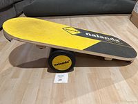 Side angle showing yellow and black balance board on the roller with nalanda branding.