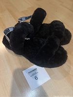 Black fuzzy Ugg sandals showing side and top view with size card 6 in front.