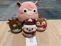 Front view showing all four Squishmallows arranged on floor with a numbered auction tag in front
