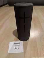 Front view of black UE Boom speaker showing large plus and minus volume buttons on fabric mesh.