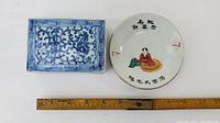 View showing both small dishes with measuring ruler for scale, rectangular blue and white patterned dish on left, round painted dish on right.
