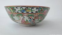 Side view of Chinese porcelain famille rose bowl showing hand-painted human figures and floral motifs on exterior.