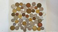 Top down view of 52 assorted coins laid out on white background showing color, size and condition variety