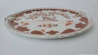 Side view of antique ceramic plate showing scalloped edge and floral painted design