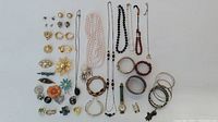 Full assortment of vintage costume jewelry laid out including brooches, earrings, necklaces, bracelets, and rings showing variety of styles and materials.