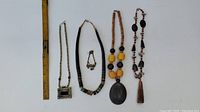 Overview of all four necklaces with varying bead styles and pendants, displayed next to a ruler for scale.