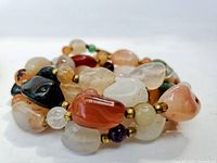 Close-up of multi-colored polished crystal and gemstone beads with gold-tone spacer beads on the necklace.