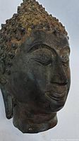 Three-quarter front left angle of Buddha head highlighting facial features and patina