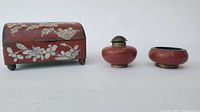 Three Chinese cloisonne items displayed together: rectangular box with floral design, incense holder with metal top, and round bowl with blue interior