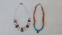 Two natural amber necklaces displayed flat on white background, showing bead details and stringing style.