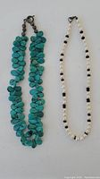 Complete view of both necklaces, showing the turquoise stone necklace and the pearl necklace.