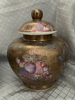 Close-up of one Japanese Satsuma lidded ginger jar showing gold background and floral design on body and lid knob