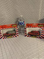 Two Solido model trucks in original packaging with a water bottle for scale, showing general lot contents and condition.