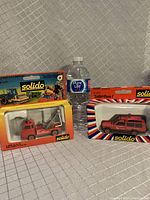 Photo showing both Solido model trucks boxed, next to a water bottle for scale