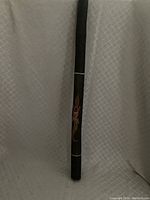 Full length view of the didgeridoo showing hand painted decoration on wooden body.