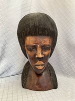 Front view of hand carved ebony bust, showing detailed facial features and wood texture.