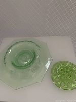 Overall view of the green depression glass bowl with octagonal rim next to the 16-hole flower frog.