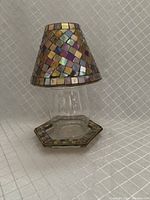Assembled candle holder showing stained glass mosaic lampshade cover, clear glass insert, and hexagonal base plate with mosaic border.