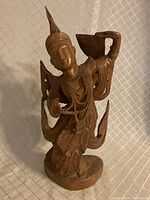 Front angled view of the hand carved teak Burmese dancing goddess statue showing intricate detailing and natural wood grain.