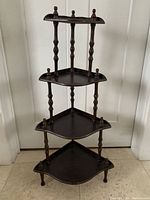 Full view of the vintage wooden corner what not shelf showing its four graduated corner shelves with turned spindle columns and finials.