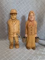 Front view of pair of carved wood figures, man and woman, standing side by side