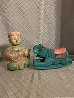 Photo showing the seated mandolin player carving holding a stringed instrument and the turquoise carved elephant with coral saddle detail side by side.