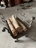 Front angle view of the wrought iron log holder filled with firewood indicating size and design details