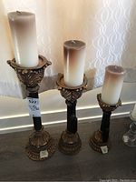 View of three resin candle holders showing size differences and condition with candles on top