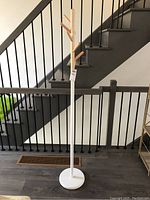 Coat rack full view showing metal base, white pole, and wooden hooks.