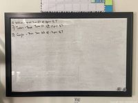 Full front view of dry erase board showing handwritten notes and two small round magnets attached to the surface.